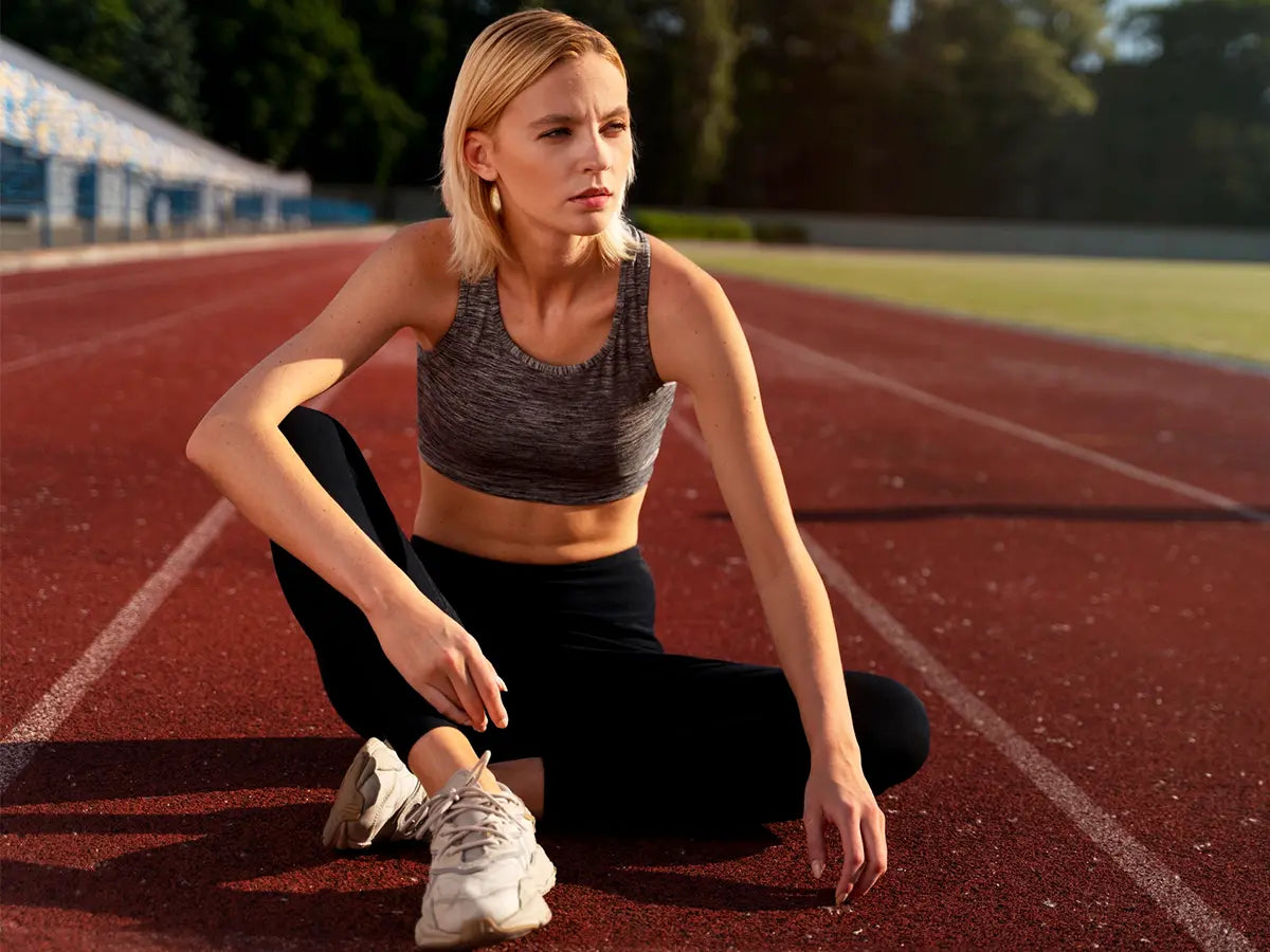 Woman resting on a running track between laps