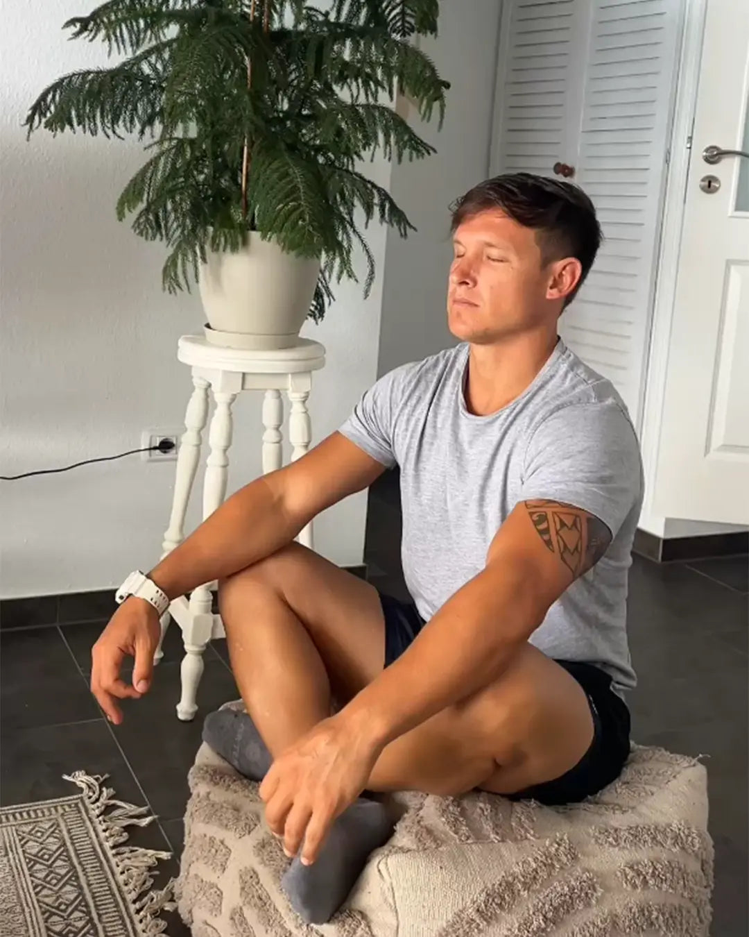 Man sitting cross-legged with his eyes closed in a calm room