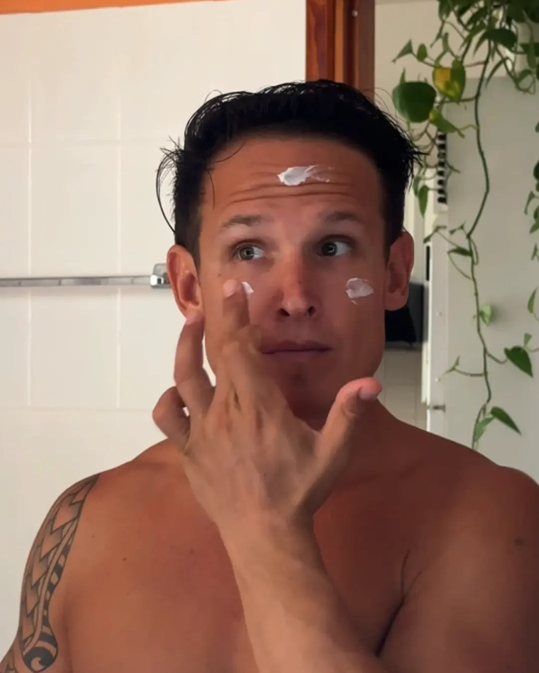 Man smoothing moisturizer onto his face after training